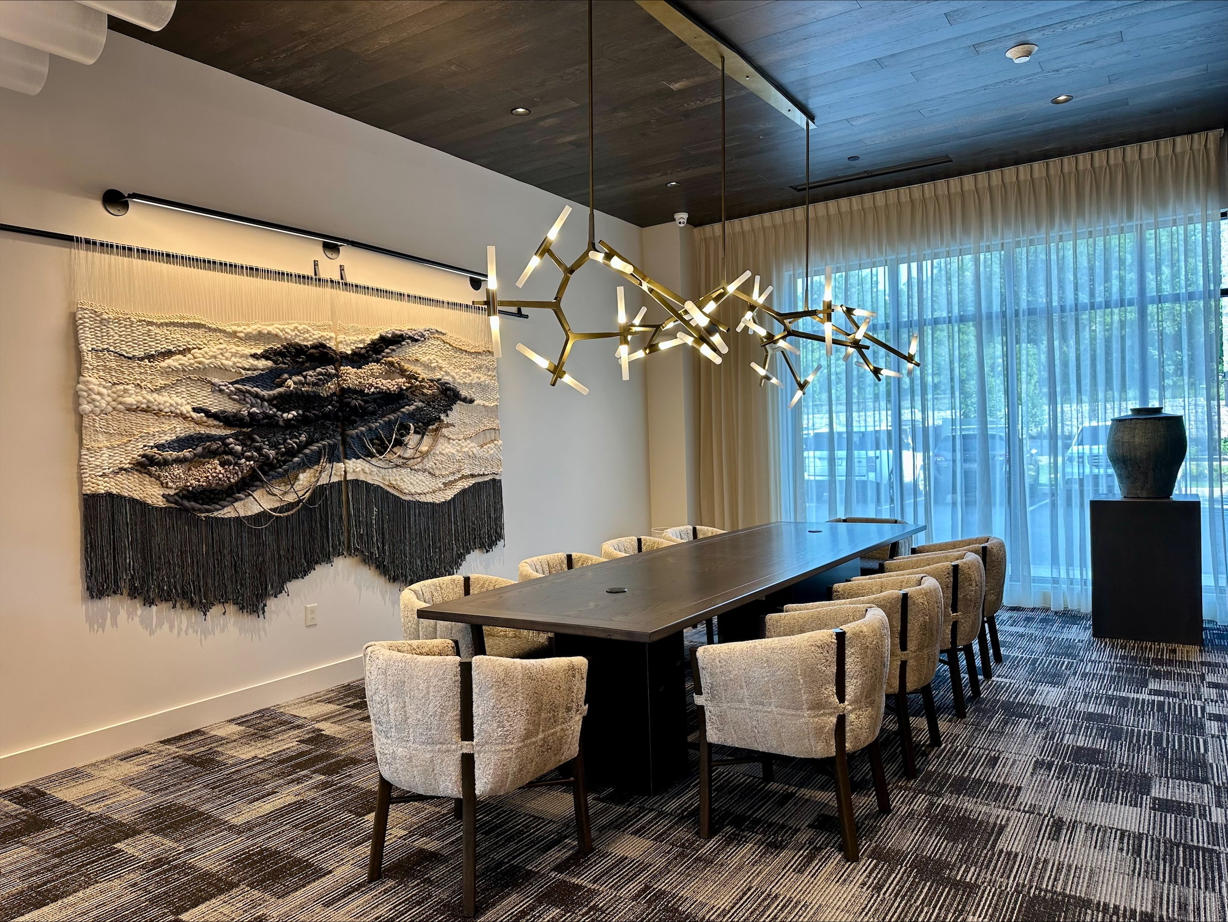 Modern conference room with a long table and chairs, decorative wall art, and large windows.