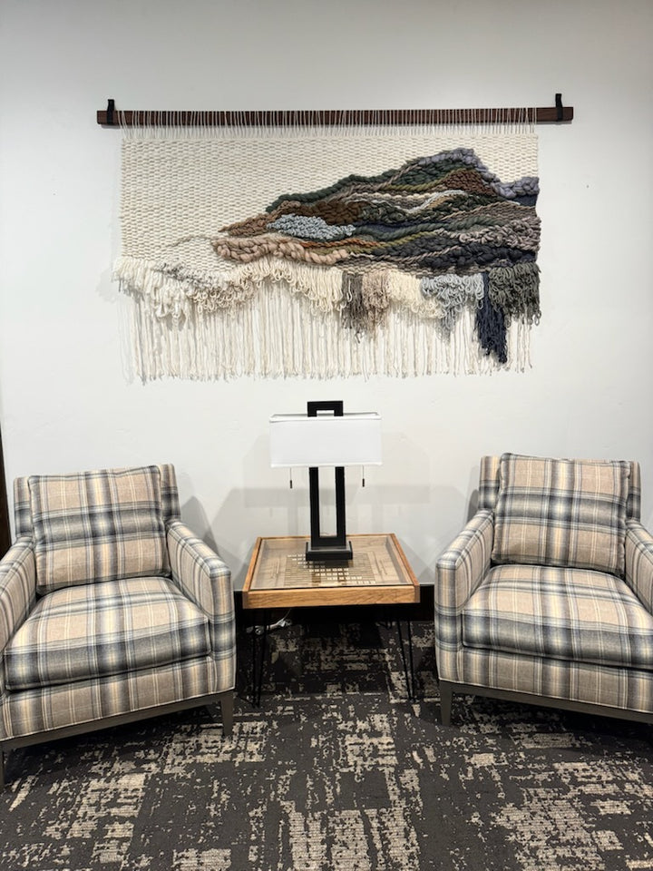 Living room with plaid chairs, a small table, and a woven wall art piece.