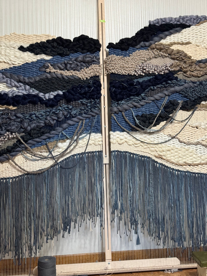 Textile with blue and black patterns on a loom