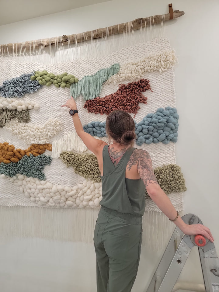 Person working on a textured wall art piece with colorful yarn.