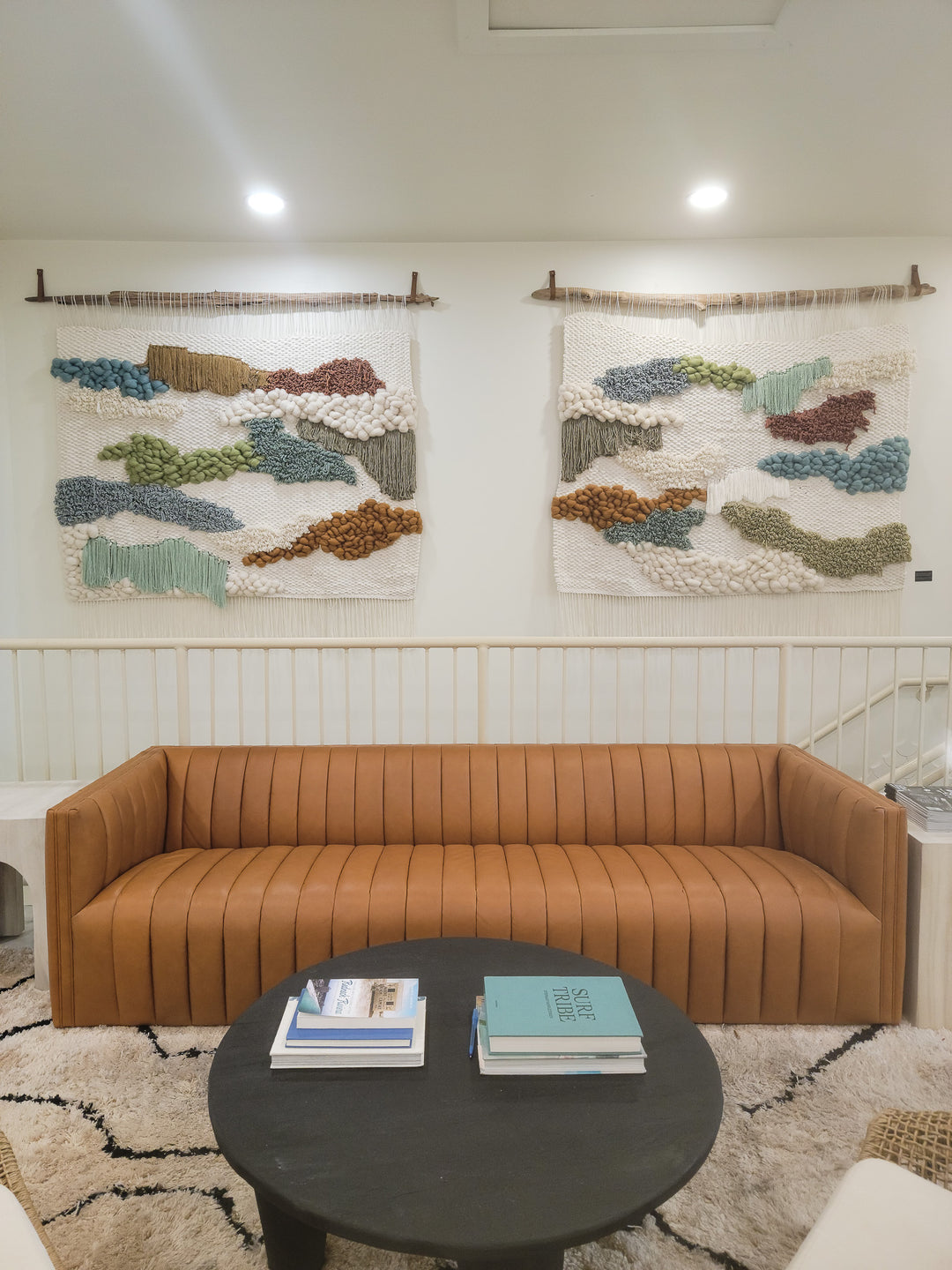 Brown sofa in a room with abstract wall art and a round dark coffee table.