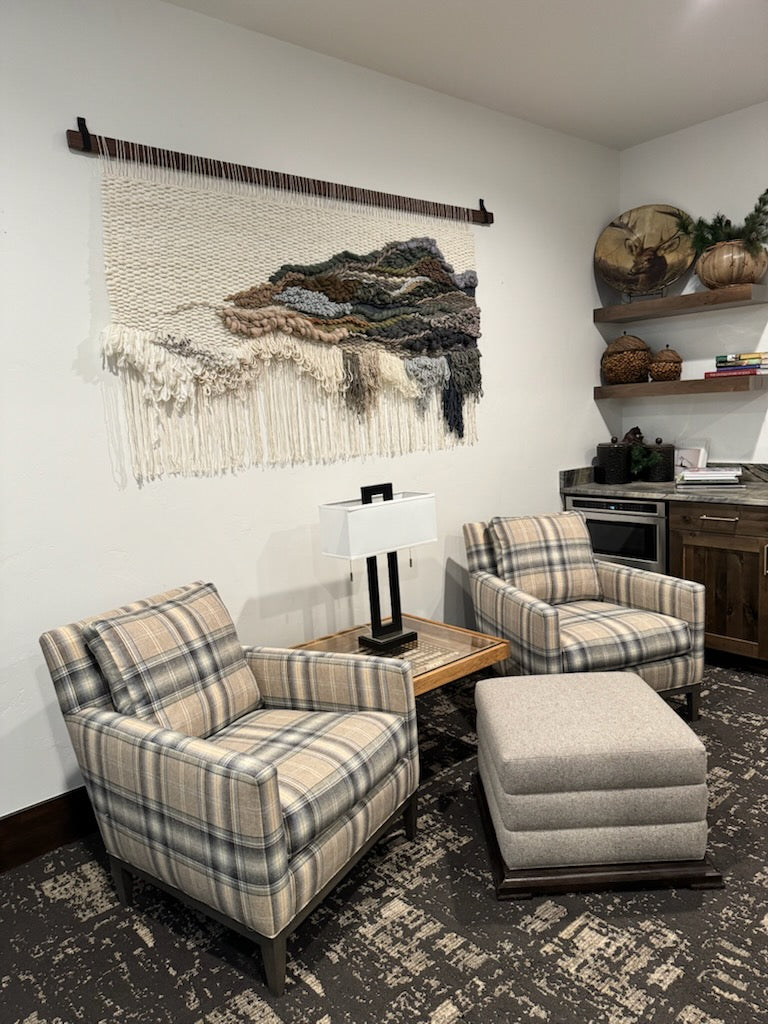 Living room with plaid armchairs, ottoman, and decorative wall art.