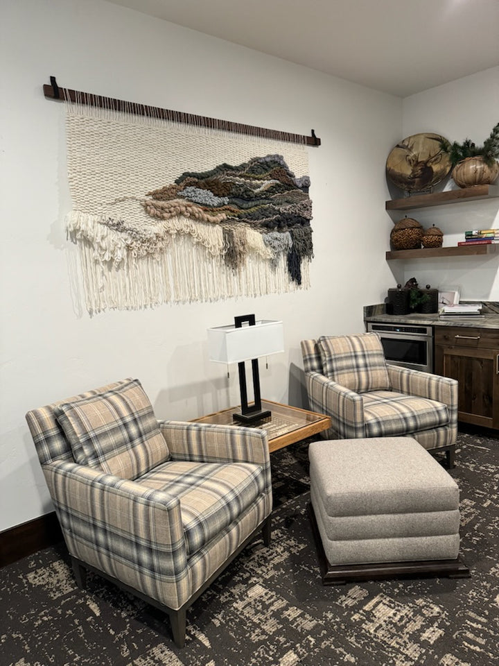 Living room with plaid armchairs, ottoman, and decorative wall art.
